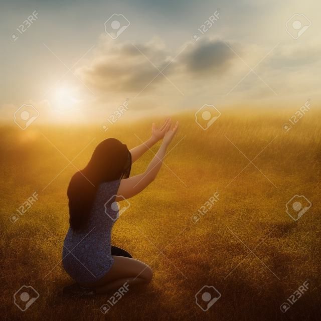 Eine Frau, die auf ihren Knien im Gottesdienst in einem Feld.