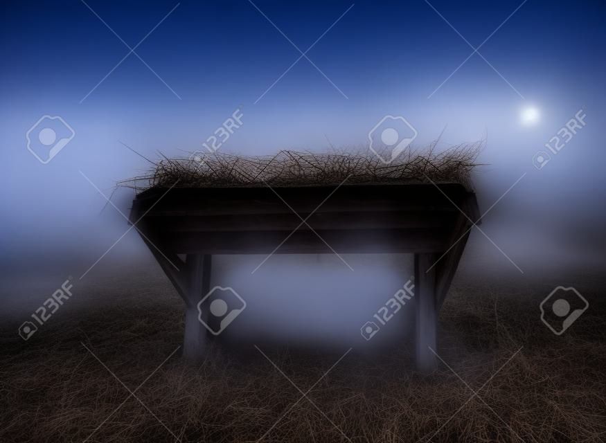 Eine leere Krippe in der Nacht unter dem Nebel.