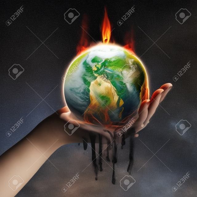 Ręka trzyma Ziemię, która topi się od ognia.