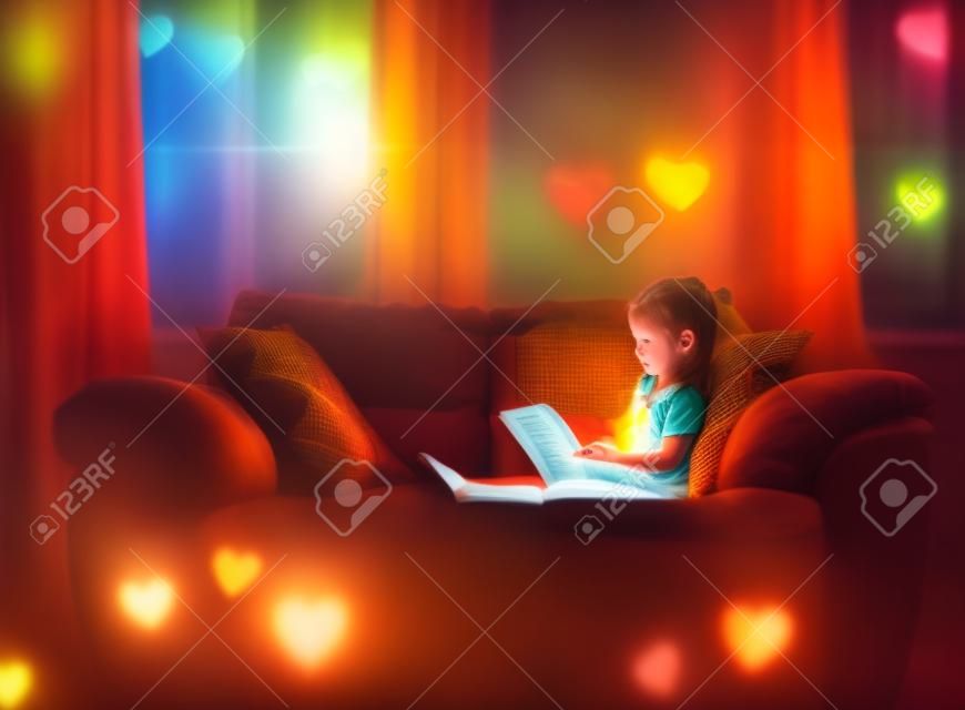 ページから輝く色の心で一人で読んでいる小さな女の子