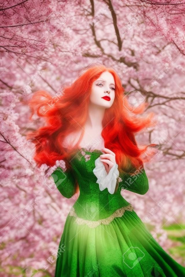 Fantasy-Porträt rothaarige Mädchen romantische Prinzessin steht im blühenden Frühlingsgarten. Blühende grüne Baumblumen. Langes Haar, rote Lippen, blasses Hautgesicht. Frau Königin mittelalterlichen Vintage kreatives Design Kleid