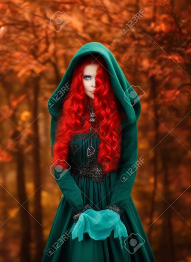 Portrait mystische Fantasie rothaarige Frauenhexe, die in die Kamera schaut. Mädchen Prinzessin. Blaugrünes mittelalterliches viktorianisches Kleid. Glamouröse Damenkönigin, rotes, langes, lockiges Haar, das im Wind weht. Herbstwald.