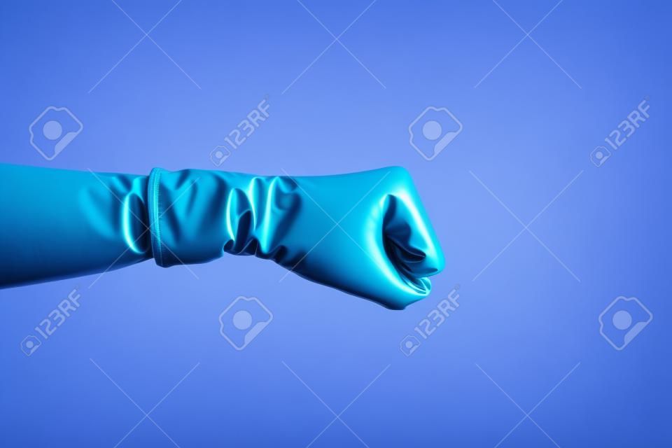 Primo piano di vista laterale di profilo della mano umana in guanti chirurgici blu che mostrano i pugni di pugilato con la mano; attacco o difesa contro i problemi. interno; ripresa in studio; isolato su sfondo rosa
