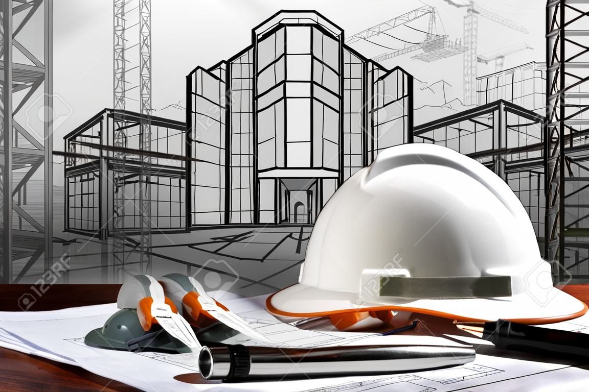 safety helmet and architect plan on wood table with sunset scene and building construction