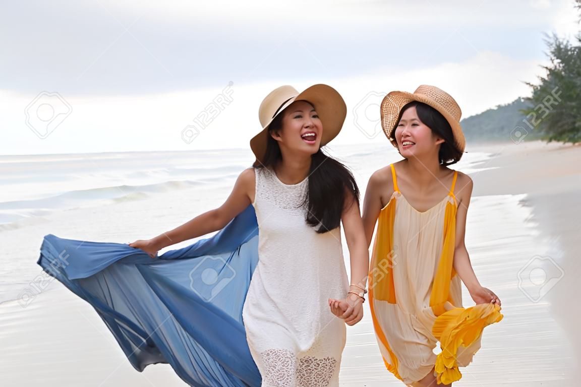 年輕的亞洲女子肖像與幸福的情感穿著漂亮的裙子走在海邊的沙灘和笑快樂利用人們對目的地度假放鬆