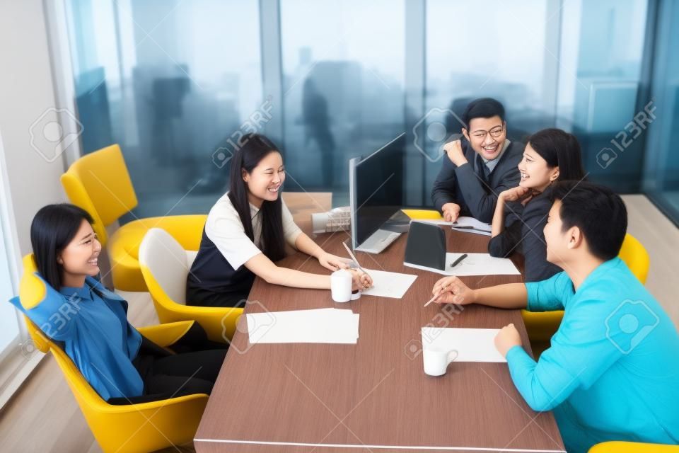 jong aziatisch freelance team ontspannen op werktafel in kantoor vergaderruimte