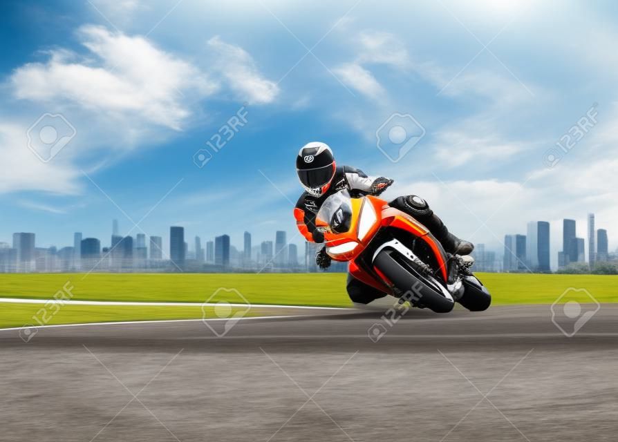 mężczyzna ubrany w kombinezon ochronny jeżdżący sportowym motocyklem wyścigowym na autostradzie o ostrym zakręcie