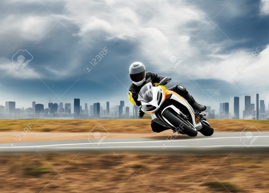 mężczyzna ubrany w kombinezon ochronny jeżdżący sportowym motocyklem wyścigowym na autostradzie o ostrym zakręcie