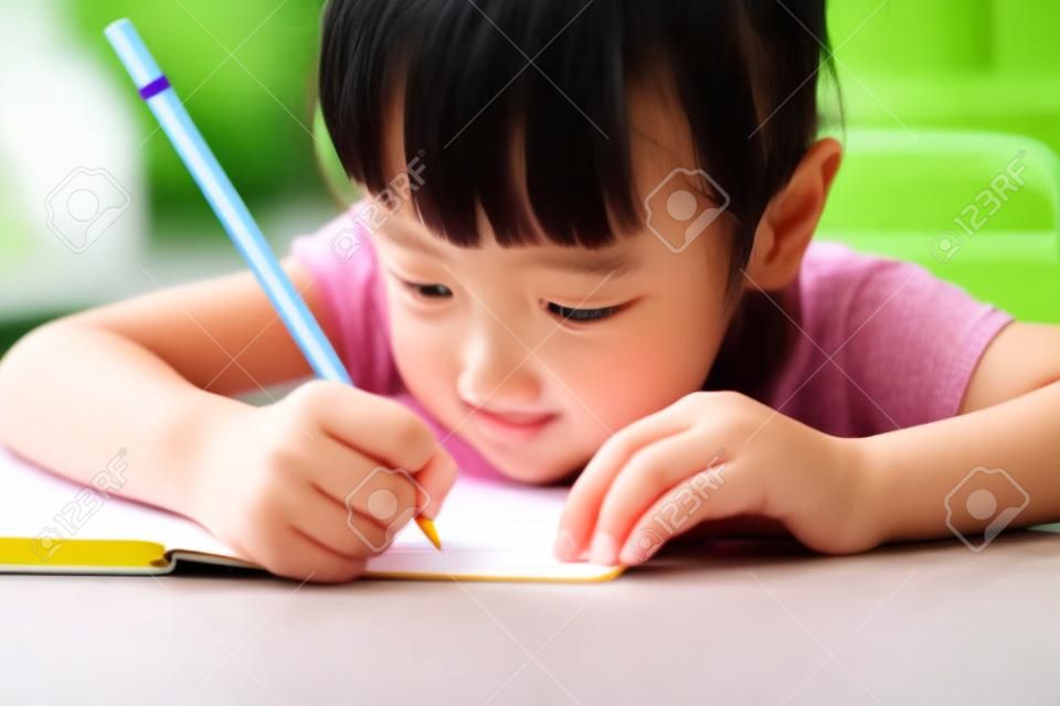 Asian Chinese little girl doing homework at outdoor cafe