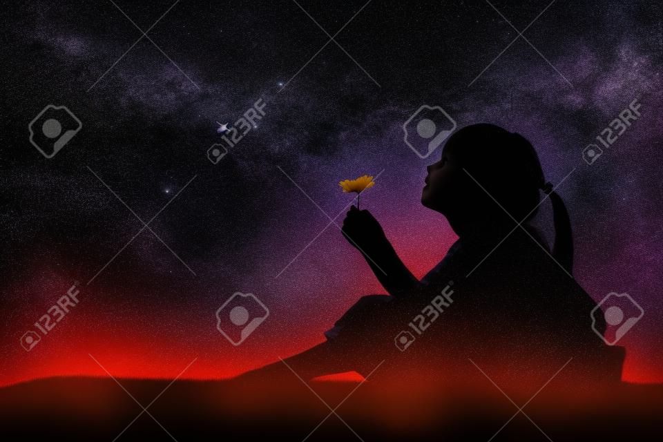 Silhouette of little girl holding a flower at the stars background