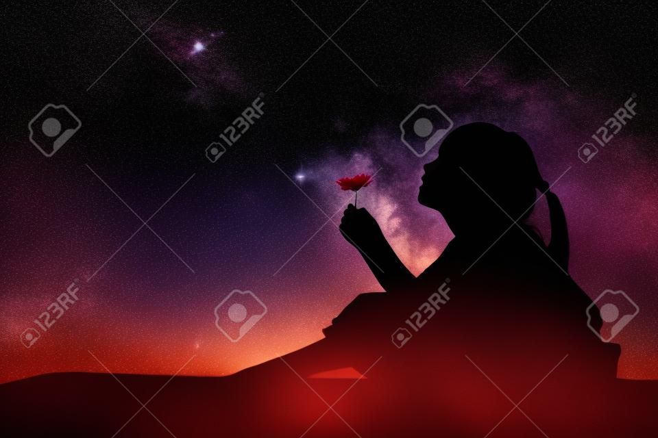 Silhouette of little girl holding a flower at the stars background