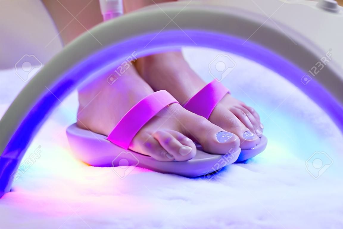Pedicure foot and nails treatment with UV lamp