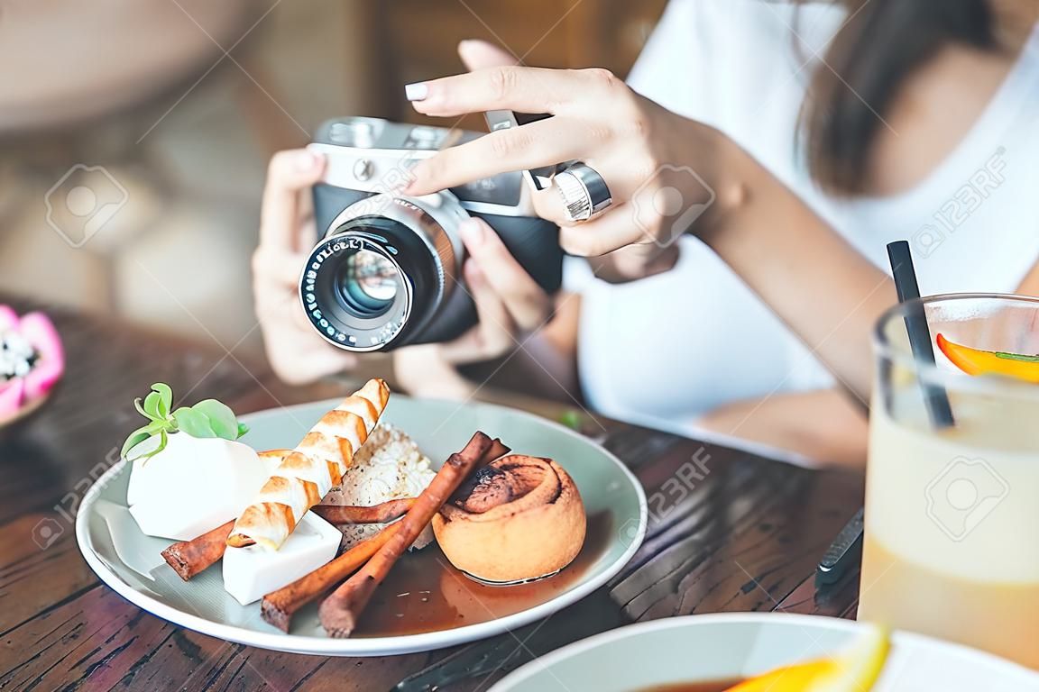 Young woman blogger taking photo of food in cafe