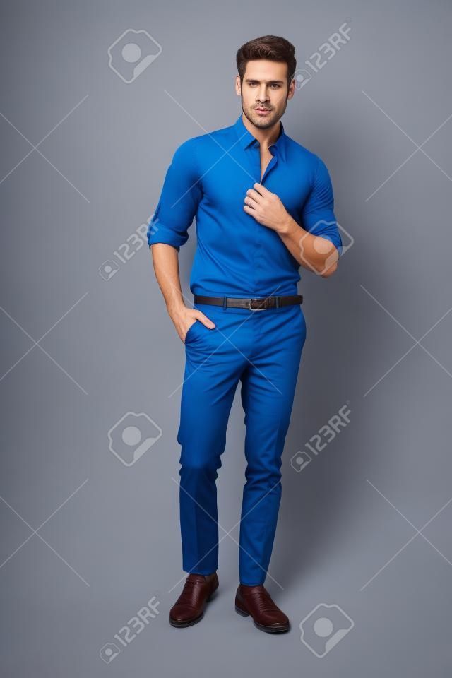 ハンサムな男は青いシャツとスタジオでポーズを着用します。