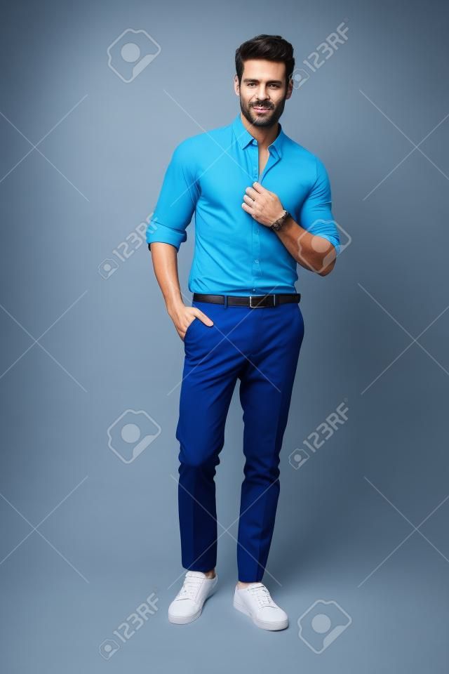 Knappe man draagt blauw shirt en poseren in studio