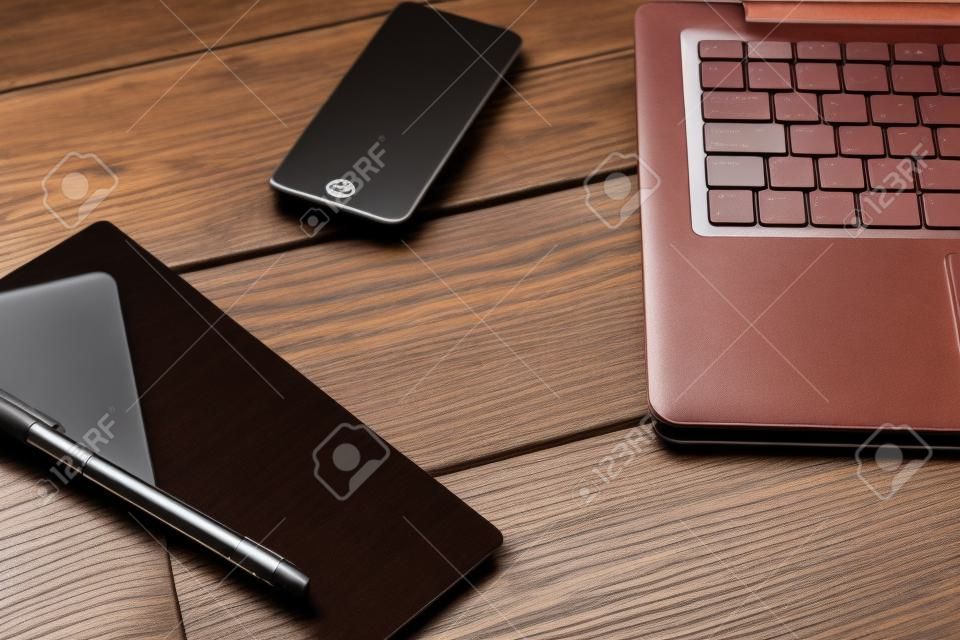 Laptop-Tastatur und Tagebuch auf dem braunen Holz-Schreibtisch
