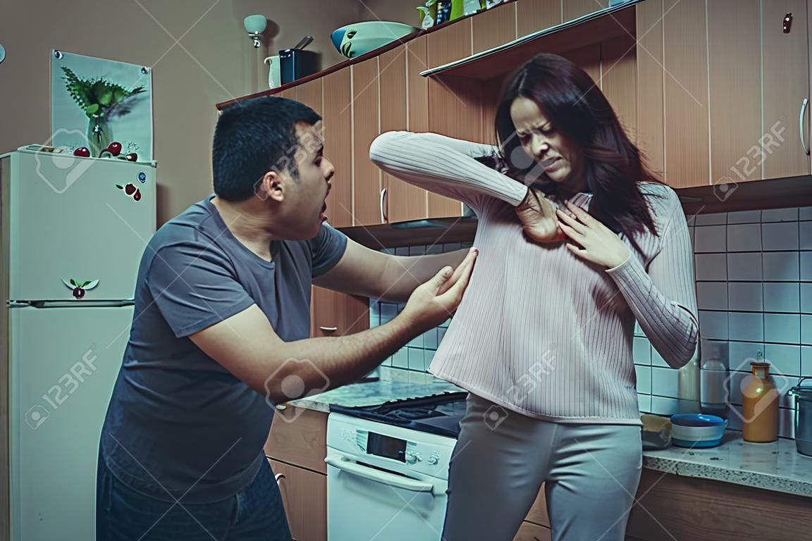 Husband in the kitchen yelling at his wife, she is afraid of him. Social problems of the family.