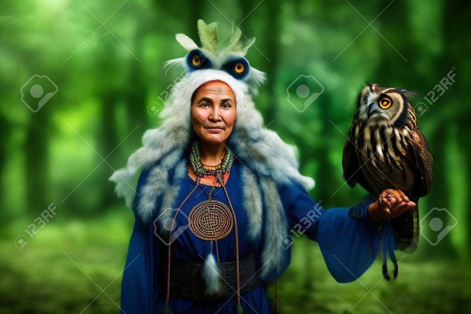 Portrait d'une femme chamane dans la forêt. Elle a un hibou grand-duc dans sa main.