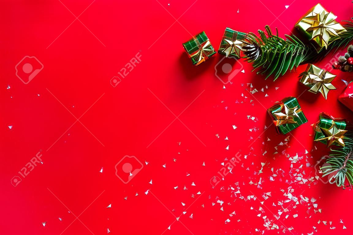 Composition de Noël. Nouvelle année. Cadeaux, branches de sapin, fond rouge. Noel, hiver, concept de nouvel an. Mise à plat, vue de dessus, espace de copie.