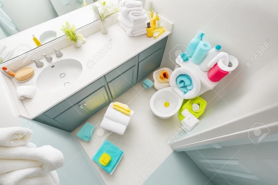 Unordentliches kleines Badezimmer mit schmutzigen Handtüchern und Reinigungsunordnung.