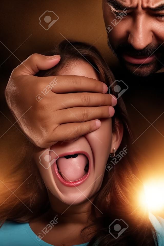 Niña maltratada por un hombre adulto que tiene una mano cubriéndose los ojos, mientras ella grita