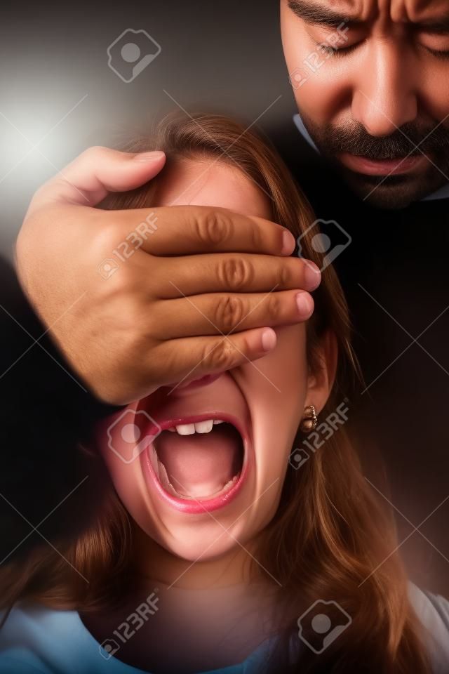 Niña maltratada por un hombre adulto que tiene una mano cubriéndose los ojos, mientras ella grita