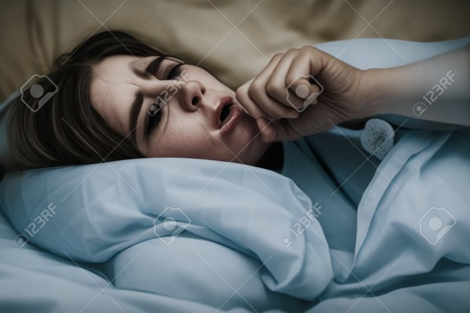 Grunge e retrato corajoso da mulher doente que põe na cama e tossindo