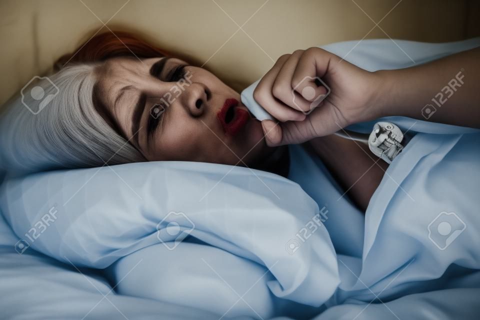 垃圾和生病的女人躺在床上咳嗽和堅韌不拔的肖像