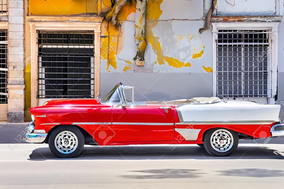 Voiture décapotable rouge classique à côté d'un bâtiment minable dans la vieille Havane