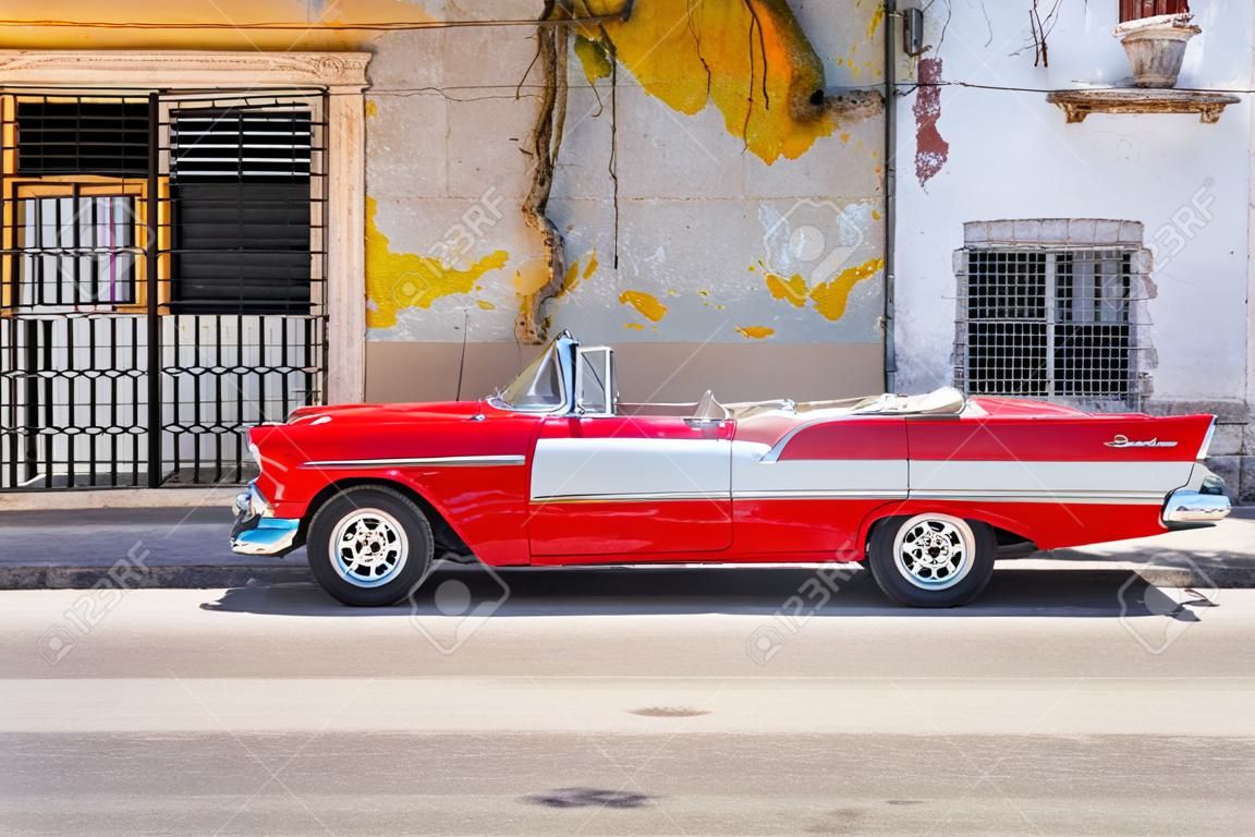 Voiture décapotable rouge classique à côté d'un bâtiment minable dans la vieille Havane