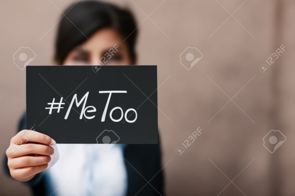 Giovane donna adulta con in mano un cartello con l'hashtag MeToo: il suo viso è sfocato