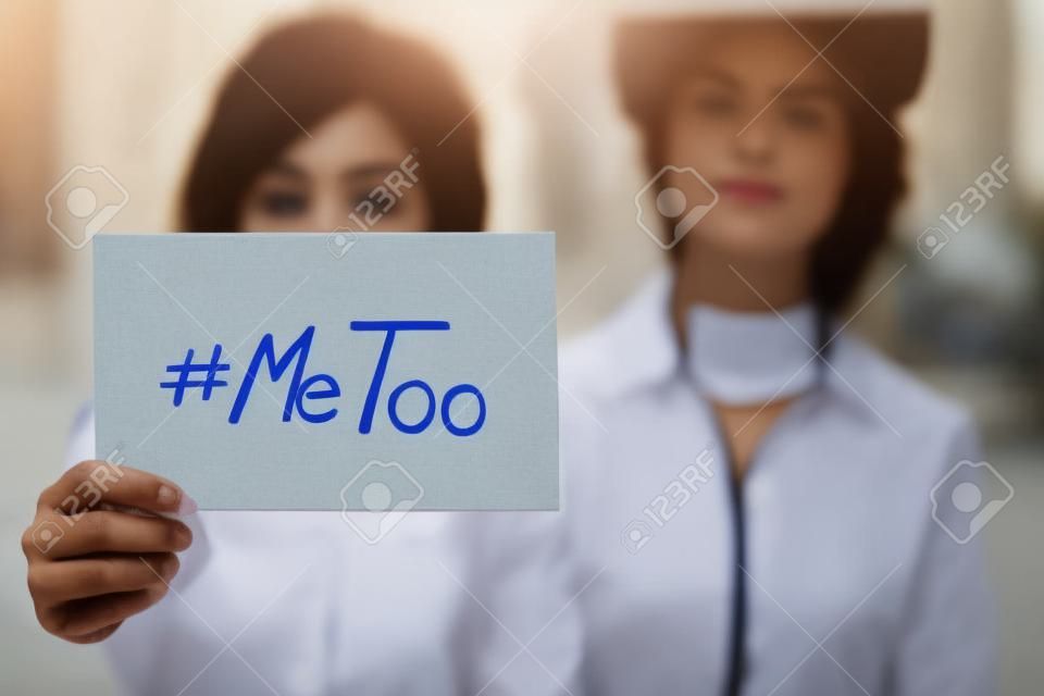 Giovane donna adulta con in mano un cartello con l'hashtag MeToo: il suo viso è sfocato