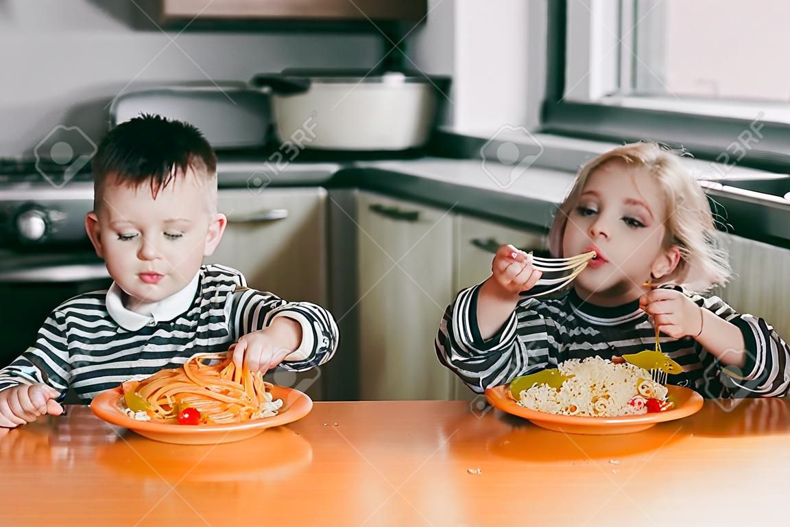 Boy and girl in the kitchen eating pasta