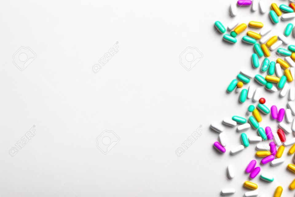 Différentes pilules éparpillées sur fond blanc. Mise à plat.