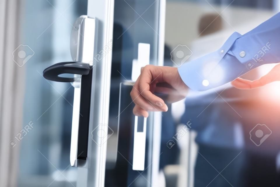 Main masculine ouvrant la porte en verre dans le bureau moderne, gros plan