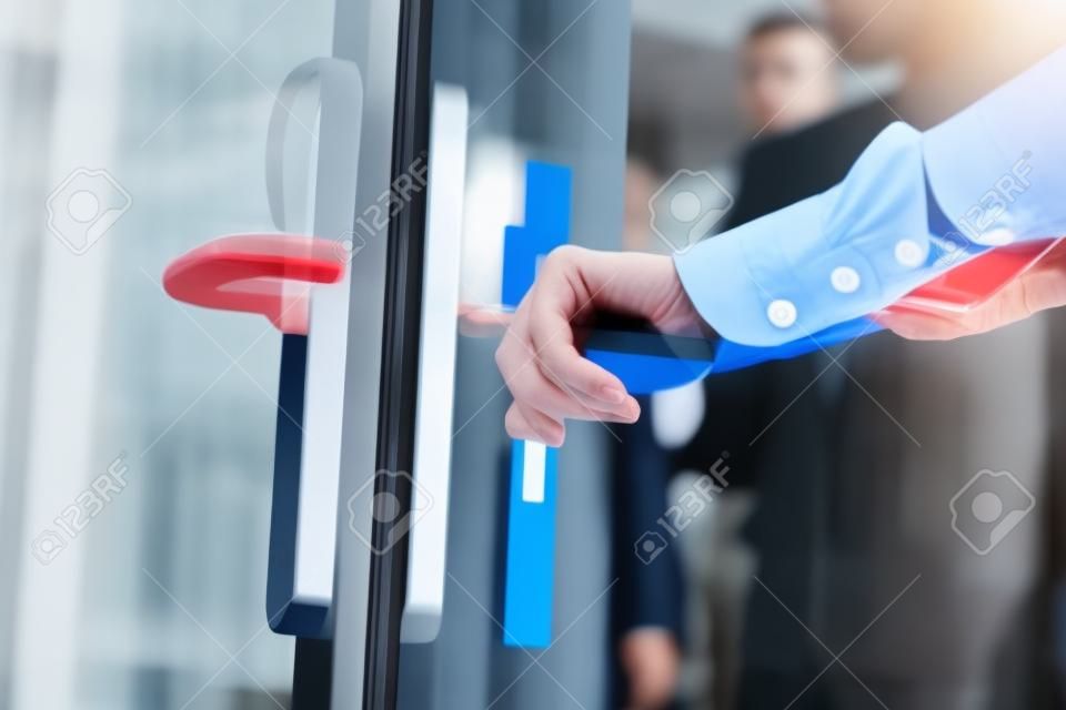 Main masculine ouvrant la porte en verre dans le bureau moderne, gros plan