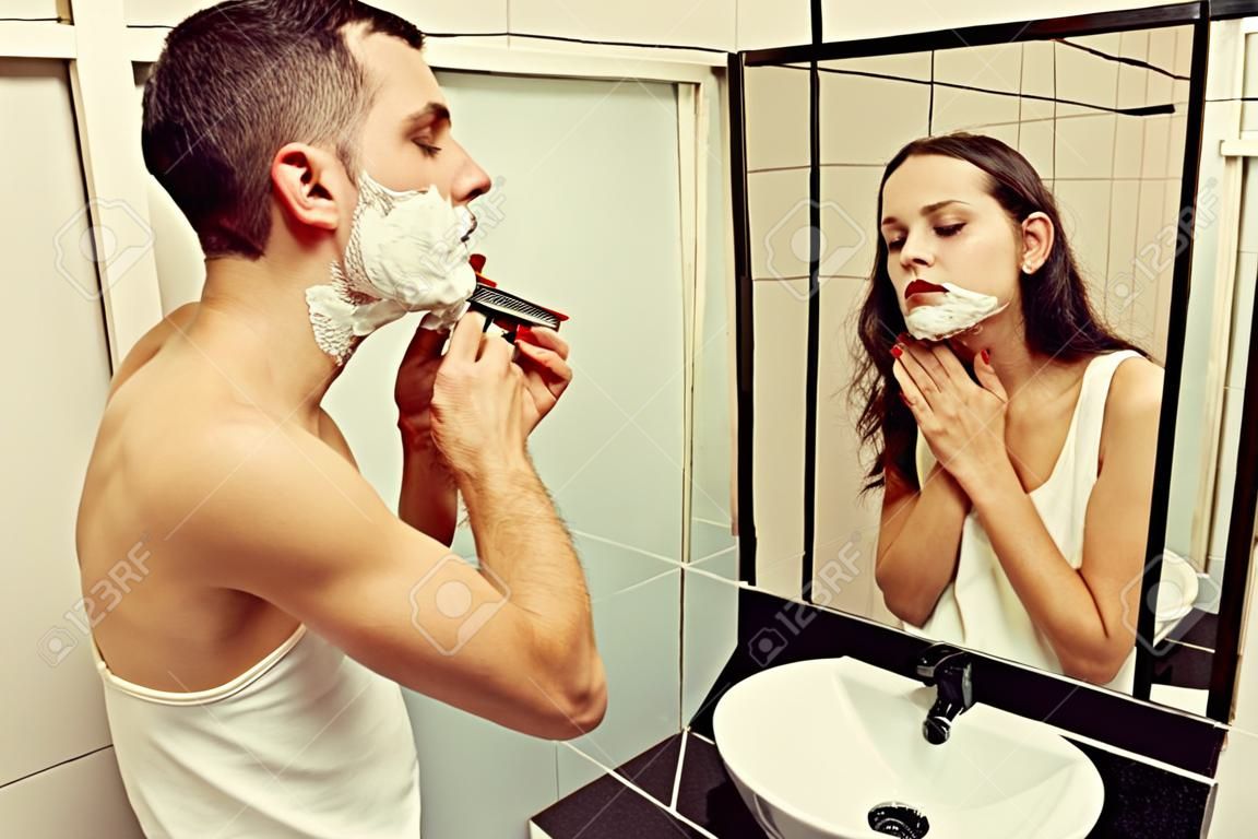 young man shaving and looking at a woman in the mirror