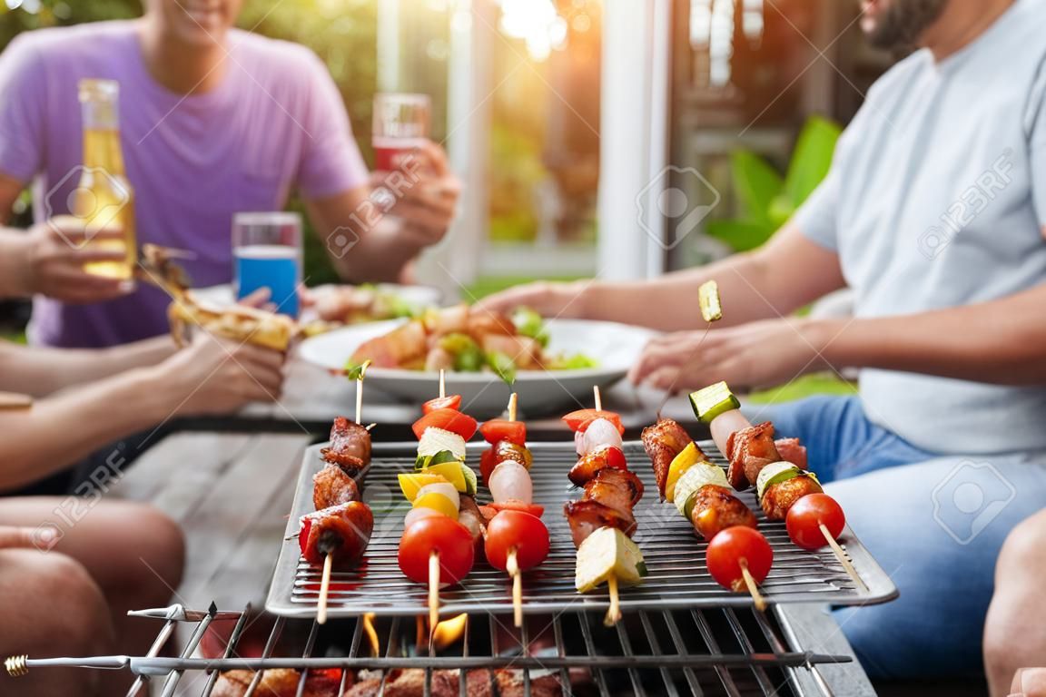 Ein Mann mit einer Grillplatte auf einer Party unter Freunden. Konzept für Essen, Menschen und Familienzeit.