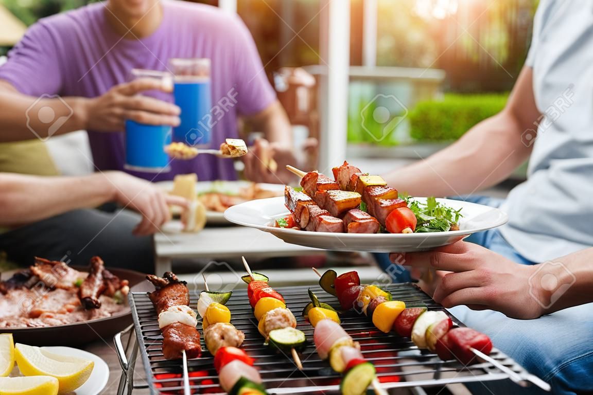 Ein Mann mit einer Grillplatte auf einer Party unter Freunden. Konzept für Essen, Menschen und Familienzeit.