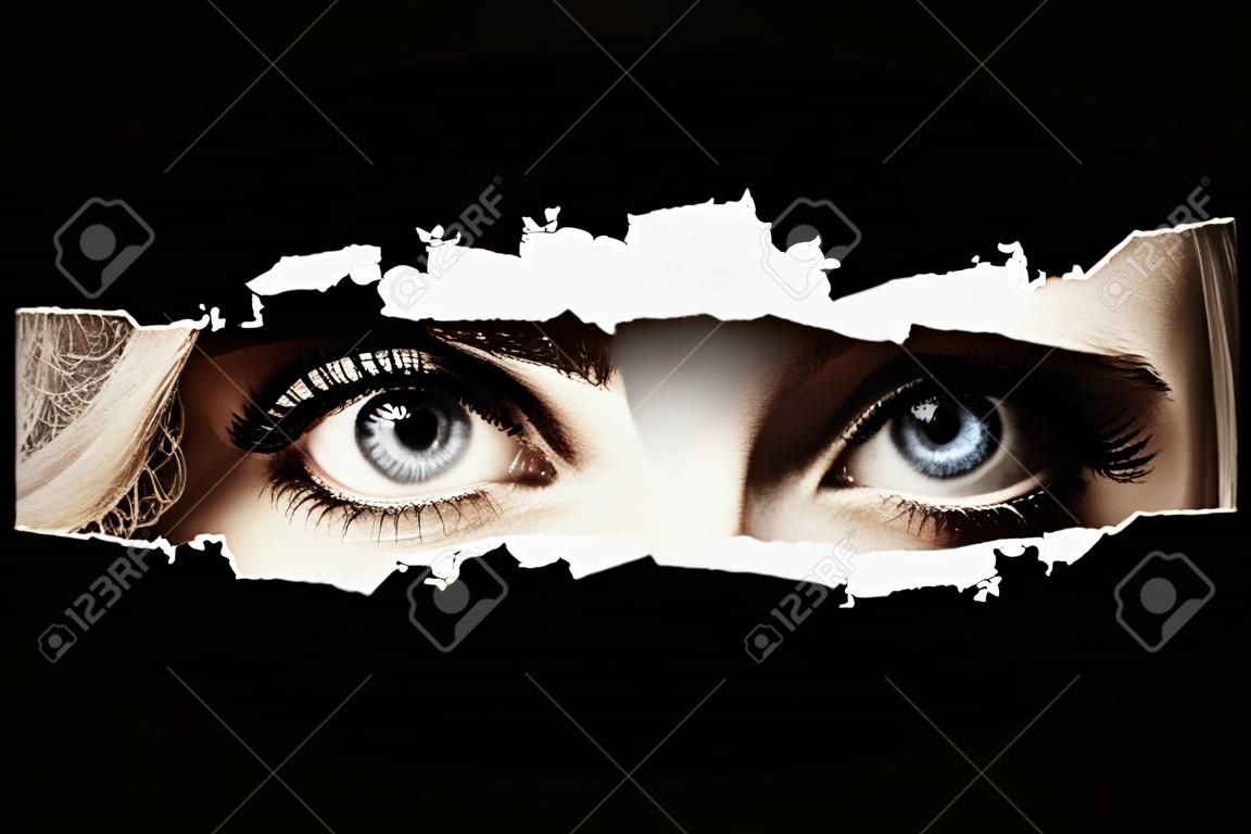 Women's blue eyes spying through a hole