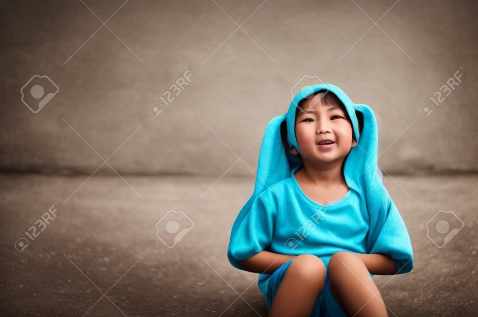 Criança asiática bonito ou menina sentar dor de estômago e doente de bactérias e gastrite com diarréia ou com fome com a mão no estômago para franzir a testa e pobre na rua com espaço