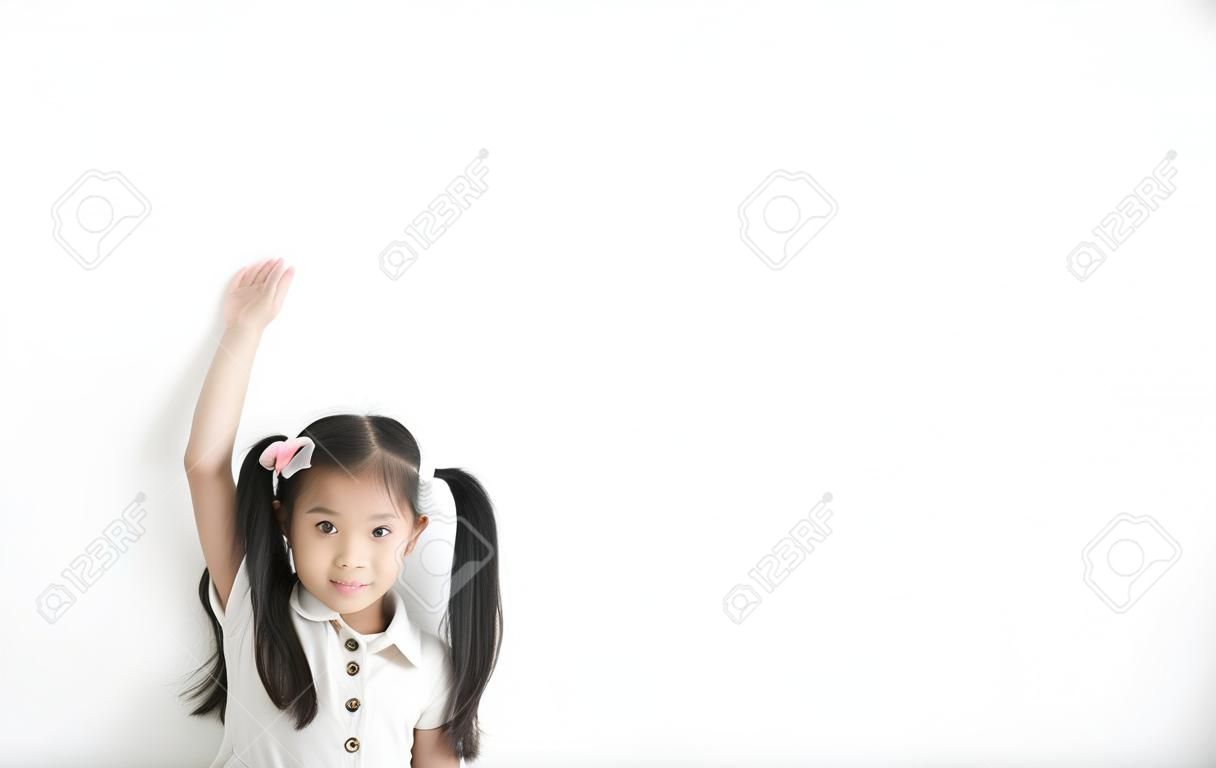 Azjatyckie dziecko słodkie lub dziecko dziewczyna szczęśliwa uśmiechnięta pokazuje wysokość lub wysokość i mierzy wysoki wzrost z 6 lat ręcznie i ramieniem od napoju mlecznego i białka na pustym tle białej ściany izolowane z przestrzenią