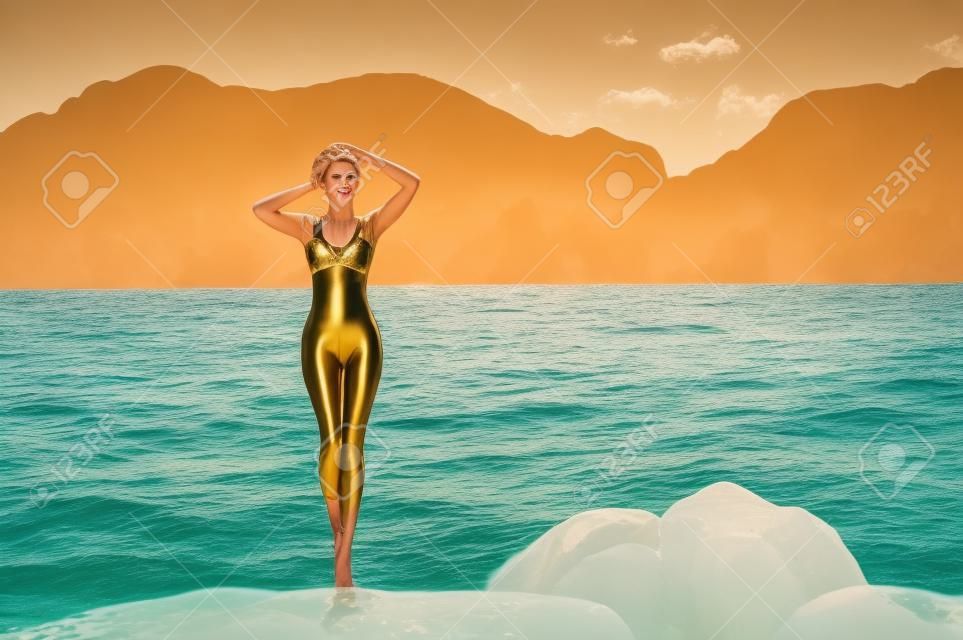 Prachtige jonge dame in een gouden badpak aan zee