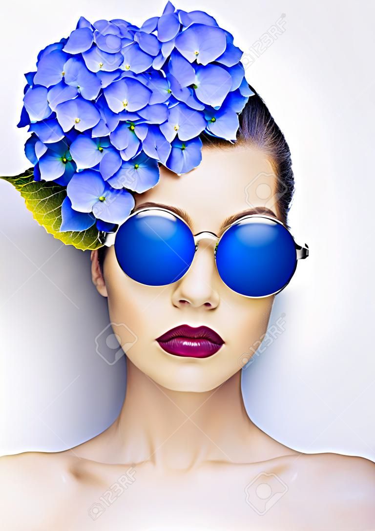 Fashion portrait of beautiful young lady with blue hydrangea