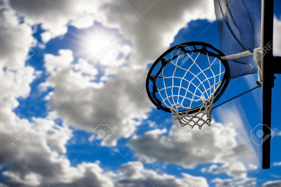 basketball hoop with net under blue sky and white clouds