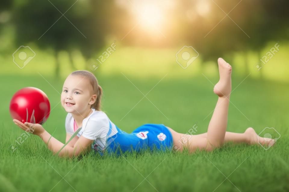 outdoor portret van jong schattig meisje gymnastiektraining met bal op gras.