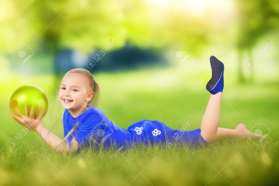 outdoor portret van jong schattig meisje gymnastiektraining met bal op gras.
