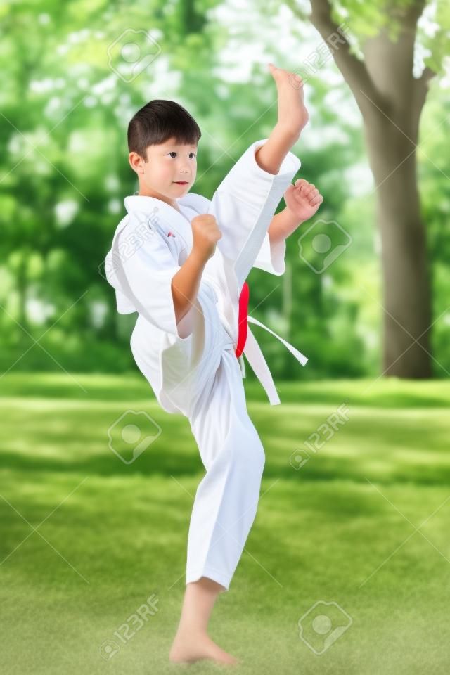 Jungen im weißen Kimono im Training Karate-Übungen im Sommer im Freien.