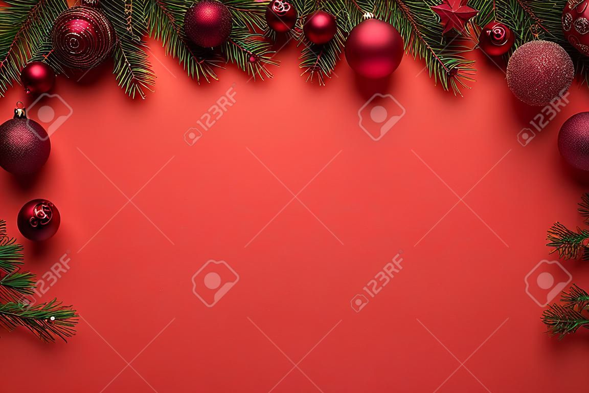 Roter Hintergrund mit Weihnachtskugeln und Tannenzweigen. Dekoration der frohen Weihnachten oder des neuen Jahres mit Kopienraum