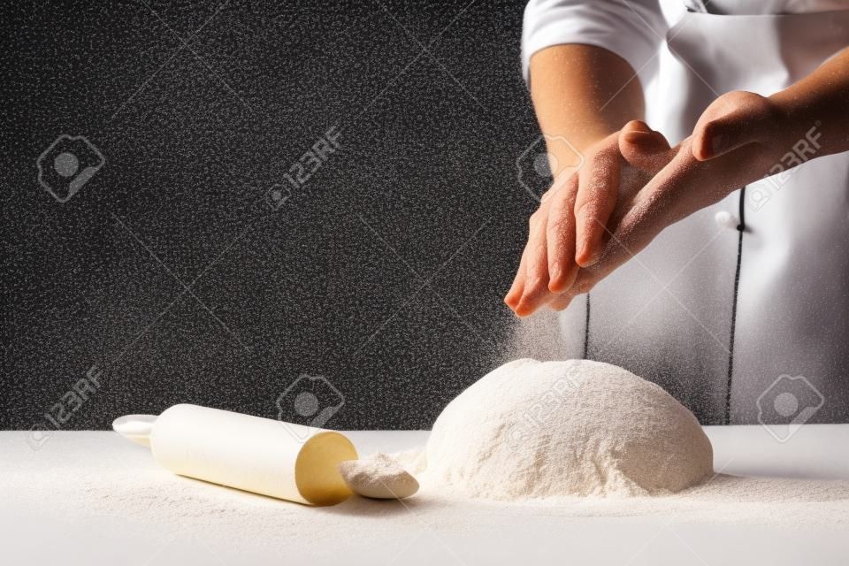 Photo de farine et de mains d'hommes avec des éclaboussures de farine. cuisson du pain. pétrir la pâte. isolé sur fond sombre. espace vide pour le texte